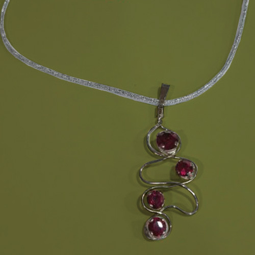 Colgante artesanal plateado con piedras fucsias, elaborado a mano por Juan Lillo Artesano, con diseño elegante y acabado de alta calidad.